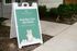 Livano Pet Center sign advertising dog day care and baths, featuring a playful illustration of a dog in bubbles, set on a green background, placed outside on a sidewalk.
