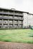 Modern apartment building with spacious balconies overlooking a lush green courtyard, perfect for leisurely outdoor activities.