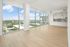Modern apartment with floor-to-ceiling windows offering panoramic city views and a sleek open kitchen design.