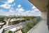 Spacious balcony offering breathtaking views of a vibrant city skyline and lush greenery, perfect for enjoying serene moments.