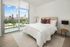 Elegant bedroom with cozy bed, soft lighting, and large windows offering a stunning cityscape view.