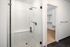 Modern bathroom with elegant glass shower and sleek white tiles leading to a spacious walk-in closet.