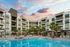Contemporary apartment complex with inviting pool and sunset view, featuring palm trees and spacious balconies.