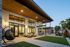 Modern apartment exterior with large windows, cozy patio seating, and lush palm trees, exuding a warm and inviting ambiance.