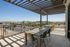 Contemporary terrace with stylish table and chairs, offering a stunning view of a lively urban landscape and clear blue skies.