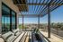 Modern balcony with stylish seating, sleek pergola, and a stunning cityscape view.