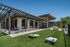 Modern patio with sleek pergola and stylish outdoor seating on lush green lawn, featuring bean bag toss game.