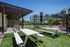 Modern apartment complex with a stylish outdoor space featuring shaded seating, lush green lawn, and inviting pool area surrounded by palm trees.