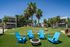 Inviting outdoor space with modern apartments, lush green landscaping, blue chairs around a stylish fire pit, and elegant palm trees.