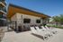 Modern outdoor lounge area with stylish sun loungers, vibrant geometric mural, and mounted TVs, perfect for relaxation and entertainment.