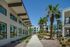 Modern apartment complex exterior with sleek architecture and lush palm landscaping against a clear blue sky.