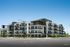 Modern apartment complex with sleek design, surrounded by lush greenery and featuring spacious balconies on every floor.
