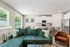 Bright open-concept living area featuring a plush green sofa, elegant dining space, and modern kitchen with sleek appliances.
