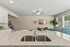 Modern open-concept living area with granite kitchen island, plush green sofa, and elegant artwork.