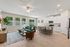 Bright and spacious open-concept living room with elegant hardwood floors, featuring a modern kitchen with a breakfast bar, stylish furnishings including a plush sectional, and abundant natural light from large windows.