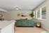 Modern living room with cozy green sofa, vibrant artwork, large windows for natural light, and stylish decor elements.
