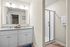 Elegant bathroom featuring dual sinks with granite countertops, modern lighting, and a sleek glass shower enclosure.