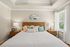 Elegant bedroom with a plush bed, stylish wooden headboard, and soothing decor. Natural light streams through large windows, creating a serene and inviting ambiance.