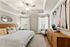 Elegant bedroom featuring a king-sized bed with patterned pillows, chic ceiling fan, and artistic coastal decor, offering a tranquil and stylish retreat.
