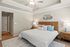 Elegant bedroom featuring modern ceiling fan, plush white bedspread, stylish wooden headboard, and cozy lamps, exuding a warm and inviting ambiance.