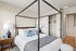Elegant bedroom with a modern canopy bed, stylish nightstands, and inviting decor in a spacious apartment.