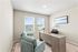 Contemporary home office with elegant desk, stylish seating, and abundant natural light through large windows.
