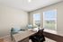 Bright home office space with elegant wooden desk, cozy chairs, and large windows offering a serene view.