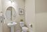 Elegant bathroom with chic oval mirror, modern pedestal sink, and stylish decor.