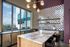 Chic modern kitchen with marble island, stylish checkered backsplash, and panoramic city views through large windows.