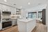 Modern open-concept kitchen with sleek appliances and spacious island flowing into a sunlit living area with floor-to-ceiling windows.