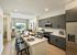 Modern open-plan kitchen and living area with sleek furnishings, stylish gray cabinetry, and abundant natural light from large windows revealing a city view.