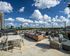 Stunning rooftop terrace with stylish seating, string lights, and breathtaking city skyline views under a clear blue sky.
