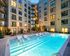 Luxurious apartment complex with a sparkling pool surrounded by modern architecture and elegant outdoor seating.