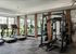 Modern fitness center with treadmills and weightlifting equipment, offering a bright and inviting workout environment with large windows and stylish mirrors.