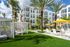 Elegant apartment complex surrounded by lush palm trees, featuring cozy cabanas and sunlit lounging areas with vibrant yellow umbrellas.