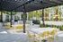 Chic outdoor patio with stylish yellow seating, glossy white tables, and modern pergola set in a lush garden oasis.