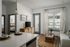 Bright and modern living area with natural light, featuring a cozy sofa, stylish floor lamp, and a sleek TV stand, adjacent to an open kitchen with elegant countertops.