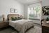 Inviting bedroom with elegant decor, featuring a cozy bed with stylish pillows, warm lighting, and a serene view through a large window.