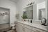 Sleek and modern bathroom design featuring a spacious vanity with elegant lighting, adjacent to a walk-in closet for ultimate convenience.