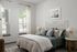 Bright and airy bedroom with a stylish bed, designer lamps, and large windows offering plenty of natural light.