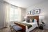 Inviting bedroom with a stylish design featuring a leather headboard, plush pillows, and two chic lamps. Large window with elegant curtains adds brightness and charm.