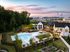 Luxurious apartment complex with a sparkling pool, vibrant greenery, and elegant modern architecture at sunset.