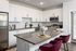 Modern kitchen with sleek white cabinets, stainless steel appliances, and a stylish island featuring chic burgundy chairs.
