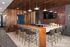 Modern kitchen with elegant wood accents, stylish bar seating, and ambient lighting, ideal for entertaining.