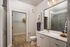 Modern bathroom featuring sleek white cabinetry, large mirror, and spacious shower with glass doors, complemented by natural wood flooring for a stylish touch.