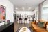 Modern open-concept apartment featuring a stylish kitchen with stainless steel appliances and sleek white cabinetry, an inviting living space with a cozy mustard sofa, and vibrant decor accents.