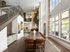 Contemporary open living space with double-height ceilings, chic dining area, and abundant natural light flowing through large windows.
