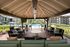 Chic apartment complex with a luxurious poolside patio under a charming pergola, featuring stylish seating and scenic views of beautifully landscaped greenery.