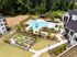 Aerial view of luxurious apartment complex with resort-style pool, landscaped gardens, modern cabanas, and vibrant community garden area, surrounded by lush forest.