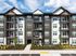 Modern apartment complex showcasing elegant architecture with balconies, surrounded by lush landscaping under a vibrant blue sky.